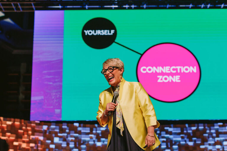 woman presenting on stage laughing