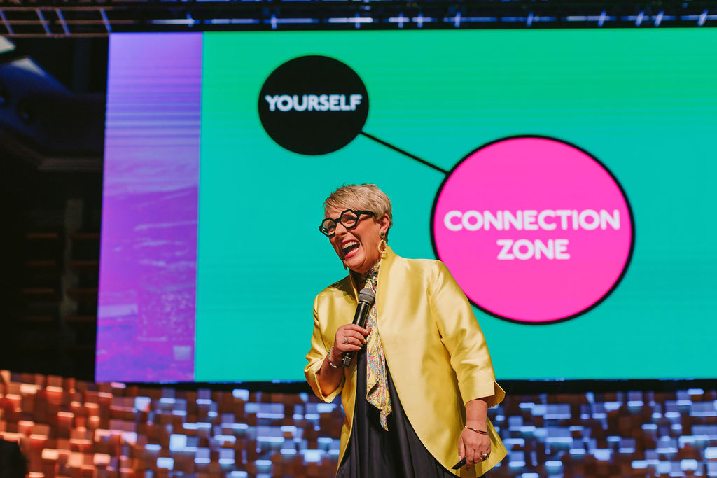 woman presenting on stage laughing