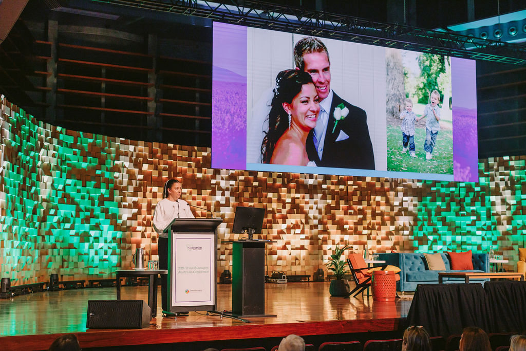woman on stage presenting at a conference