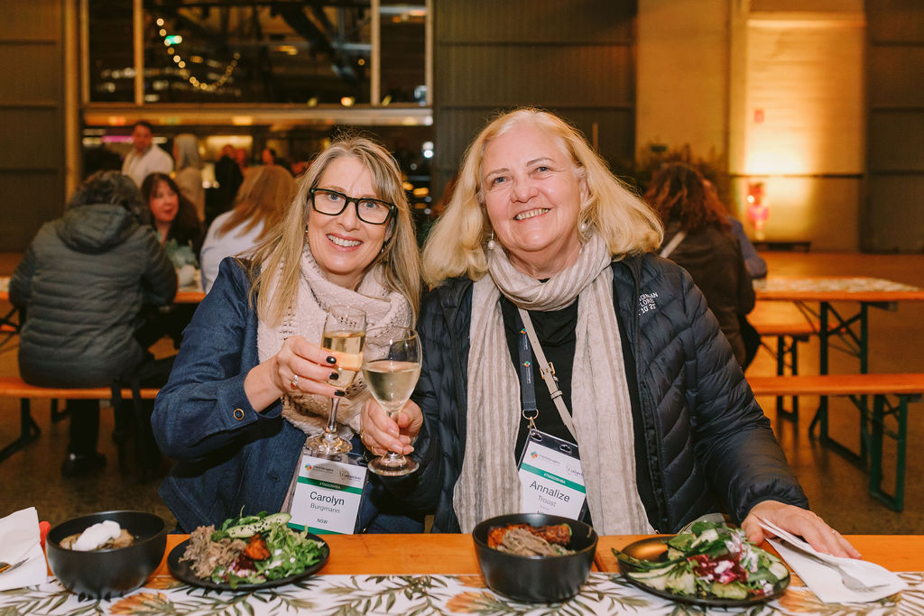 two women posing for a photo, seated, at a conference